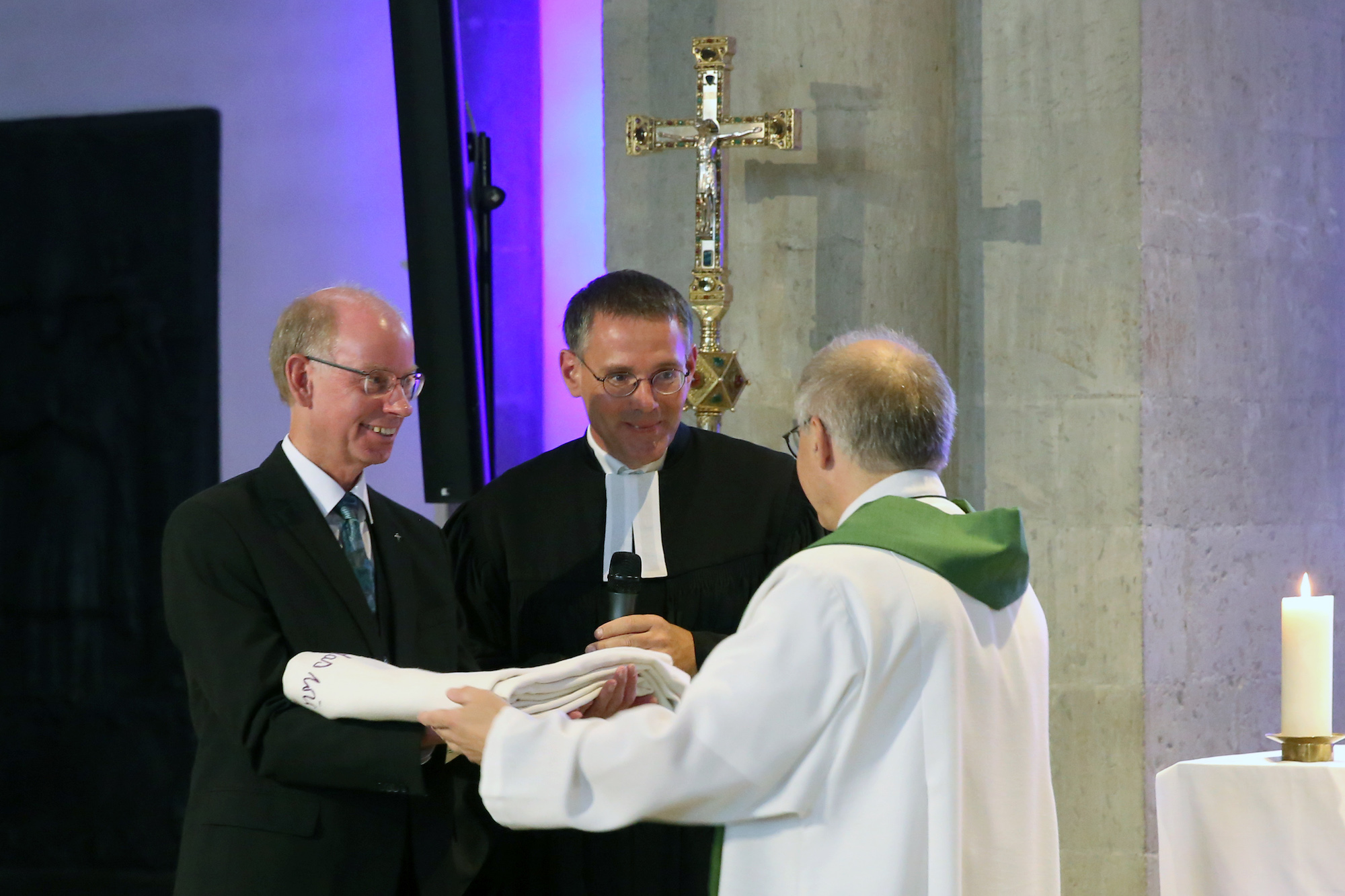 Propst Peter Blättler übergibt das Mönchengladbacher Altartuch an die evangelischen Geschwister Pfarrer Stephan Dedring (l.) und Pfarrer Till Hüttenberger.